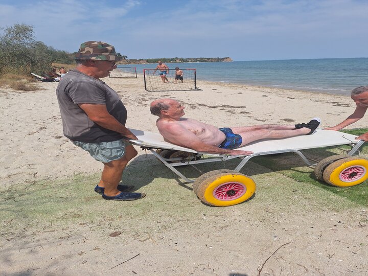 Buitenhof Reizen voor mensen met een verstandelijke beperking - zorg - Grieks Macedonie - reiziger met strandrolstoel in het water Buitenhof Reizen voor mensen met een verstandelijke beperking - zorg - Grieks Macedonie - reiziger met strandrolstoel in het water