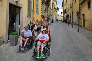 Buitenhof Reizen voor mensen met een verstandelijke beperking - Zorg - Italiaanse lekkernijen in Toscane - groepsfoto wandelend in een dorp Buitenhof Reizen voor mensen met een verstandelijke beperking - Zorg - Italiaanse lekkernijen in Toscane - groepsfoto wandelend in een dorp