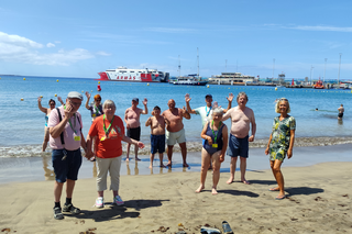 Buitenhof Reizen voor mensen met een verstandelijke beperking - Rustig Aan - Stranden van Tenerife - groep reizigers op het strand met handen in de luc Buitenhof Reizen voor mensen met een verstandelijke beperking - Rustig Aan - Stranden van Tenerife - groep reizigers op het strand met handen in de luc