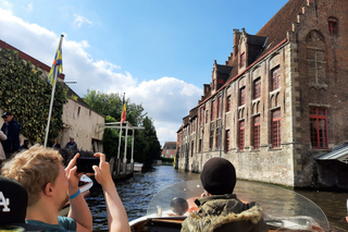 Buitenhof Reizen - jongeren - Zomers Zeeland - begeleide groepsreizen met een verstandelijke beperking - Boottoch waarop een reiziger een foto maakt met gebouwen Buitenhof Reizen - jongeren - Zomers Zeeland - begeleide groepsreizen met een verstandelijke beperking - Boottoch waarop een reiziger een foto maakt met gebouwen