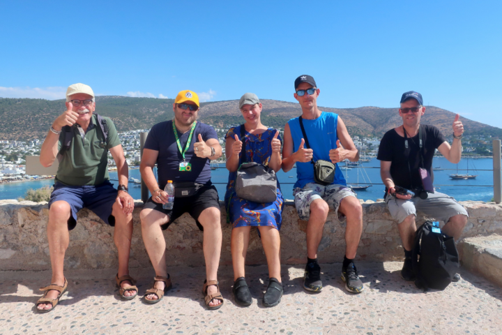 Buitenhof Reizen - Bodrum - begeleide vakanties voor mensen met een beperking - Blije reizigers op een rij met uitzicht op zee Buitenhof Reizen - Bodrum - begeleide vakanties voor mensen met een beperking - Blije reizigers op een rij met uitzicht op zee
