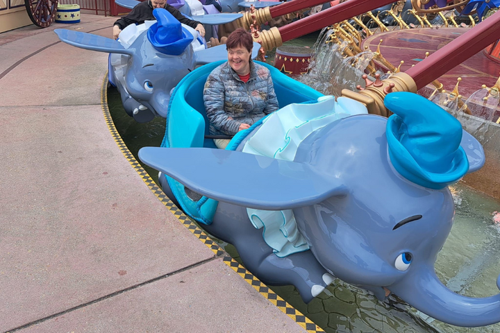 Buitenhof Reizen - Disneyland - begeleide vakanties voor mensen met een beperking - Reiziger in Dumbo attractie Buitenhof Reizen - Disneyland - begeleide vakanties voor mensen met een beperking - Reiziger in Dumbo attractie