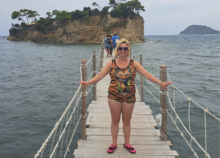 Buitenhof Reizen voor mensen met een verstandelijke beperking - Jongeren - Zonnig Zakynthos - Reiziger op een bruggetje in het water met rots op de achtergrond Buitenhof Reizen voor mensen met een verstandelijke beperking - Jongeren - Zonnig Zakynthos - Reiziger op een bruggetje in het water met rots op de achtergrond